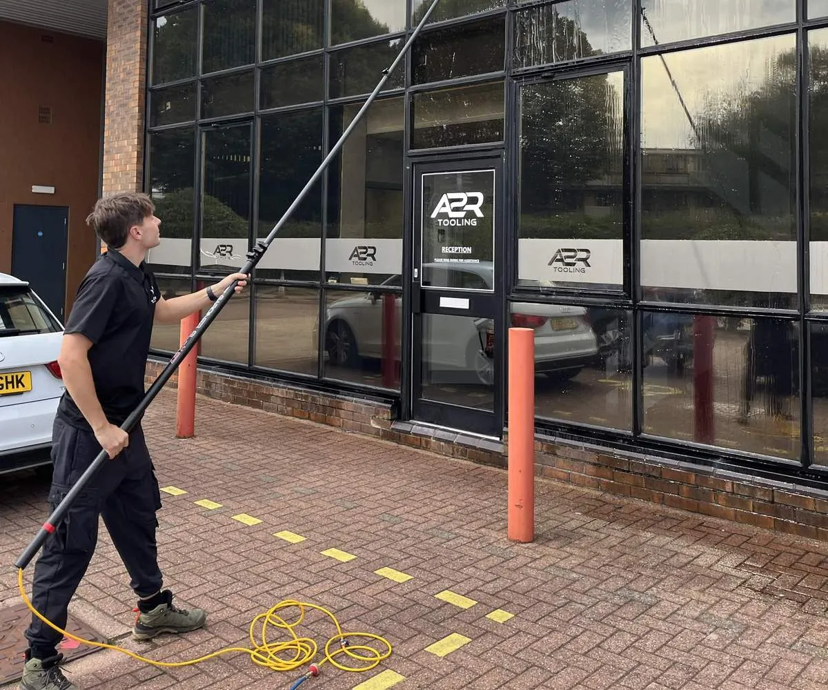 Trident Cleans window cleaner using a pure water pole on a commercial building